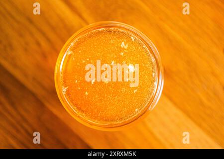 Vue de dessus de Sweet Golden Bee Honey avec des bulles fraîchement récoltées debout sur une surface en bois gros plan Banque D'Images