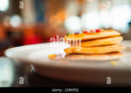 Pile de crêpes avec miel d'abeille tombant vers le bas et lentilles au chocolat comme garniture Banque D'Images