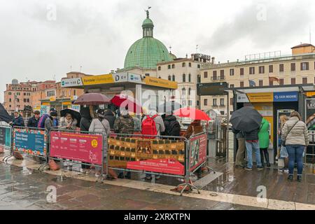 Venise, Italie - 3 février 2018 : de nombreux touristes attendent des billets devant la gare maritime Ferrovia des transports publics à la pluie humide hiver. Banque D'Images