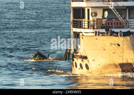 Louxor, Égypte ; 16 janvier 2024 : vivez l'heure d'or lors d'une croisière sur le Nil alors que des vendeurs locaux dans de petits bateaux proposent des chilabas traditionnels. C'est unique. Banque D'Images