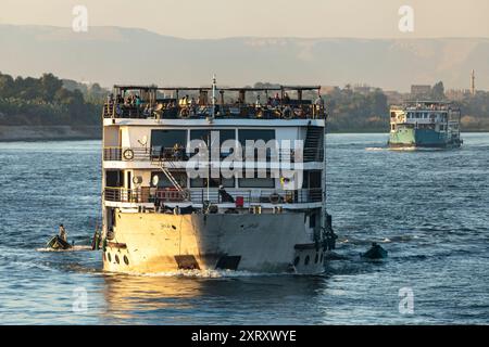 Louxor, Égypte ; 16 janvier 2024 : assistez à la vie quotidienne animée sur le Nil alors que les vendeurs locaux en petits bateaux offrent leurs marchandises aux passagers de croisière. Banque D'Images