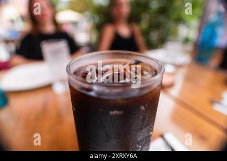 Verre frais froid de Coca-Cola boisson gazeuse avec glaçons sur une table en bois lors d'une chaude journée d'été Banque D'Images