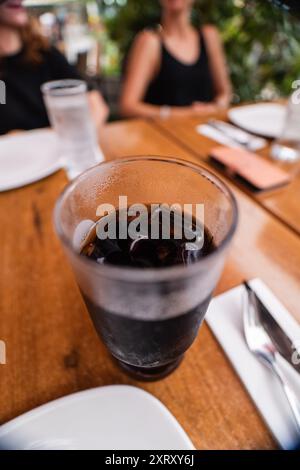 Verre froid de Coca-Cola boisson gazeuse avec glaçons sur une table en bois Banque D'Images