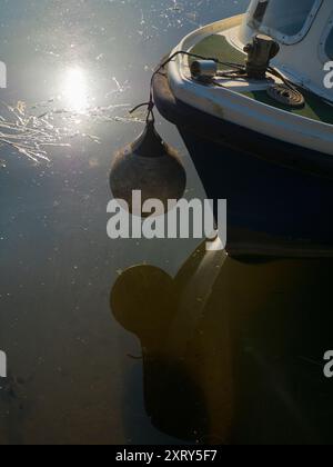 Bateau de plaisance et bouée amarrés sur la Tamise, le soleil se reflétant sur les eaux. Vu à Radley Boathouse ; construit en 1849, ce centre bien équipé pour l'aviron et les sports nautiques a la chance d'être situé sur un tronçon particulièrement beau de la Tamise. Mais voici la question : comment s'appelle la bouée ? Une petite recherche montre qu'il s'appelle différemment pare-chocs, garde-boue, boule de bateau, bouée d'amarrage, bouée d'ancre et probablement plusieurs autres noms que j'ai manqués. Mais nous soucions-nous vraiment, de toute façon ? Banque D'Images