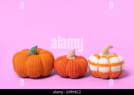 Citrouilles tricotées orange et rayées sur fond violet. Concept d'Halloween. Histoire d'automne tricotée avec vos propres mains. Banque D'Images