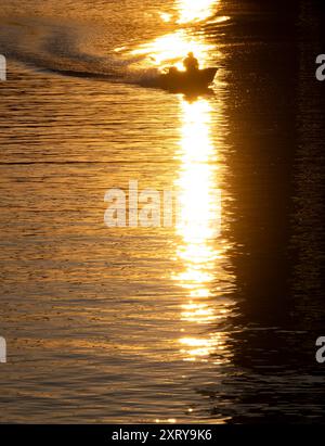 12 août 2024, Hesse, Francfort-sur-le-main : un bateau traverse la main aux dernières lueurs du jour. Les températures les plus élevées de l’été jusqu’à présent devraient être atteintes dans les prochains jours. Photo : Boris Roessler/dpa Banque D'Images