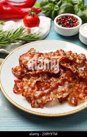 Tranches de bacon frit savoureux et différentes épices sur la table en bois bleu clair Banque D'Images