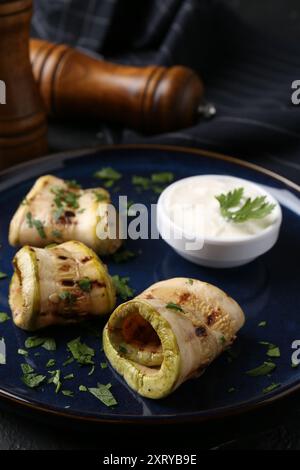 Savoureuses tranches de courgettes grillées servies avec sauce sur table Banque D'Images