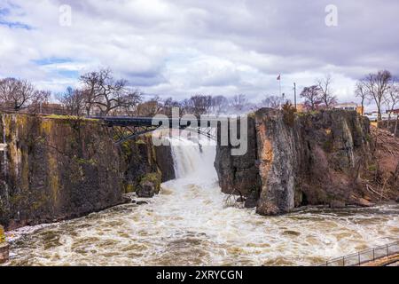 Paysage printanier dans le New Jersey avec les chutes de Paterson descendant la rivière Passaic, encadrées par des paysages de montagne et un ciel nuageux. Banque D'Images