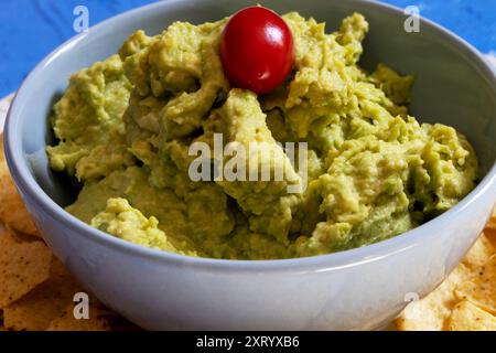 Version brésilienne de guacamole décorée de tomates cerises à l'intérieur et d'un bol bleu. Banque D'Images