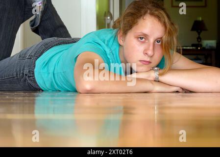 Jeune femme, 16 ans, fille adoptive de l'Ukraine lève les yeux du plancher de bois frais et repos réfléchi, Vermont, États-Unis Banque D'Images