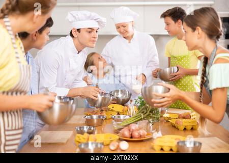 Les apprentis chefs apprennent à battre correctement les œufs avec un fouet en cours de cuisine Banque D'Images