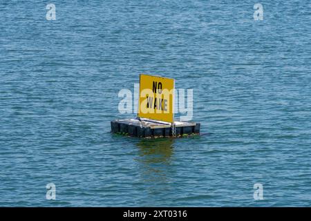 Un panneau jaune No Wake flottant sur l'eau Banque D'Images