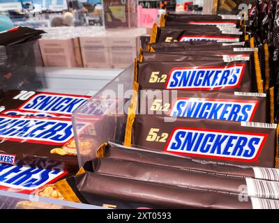 Bavière, Allemagne - 12 août 2024 : les tablettes de chocolat Snickers dans des packs familiaux sont présentées sur les étagères des supermarchés *** Snickers Schokoriegel in Familienpackungen werden im Supermarktregal präsentiert Banque D'Images