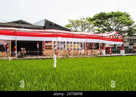 Bandung Regency, Indonésie. 12 août 2024. Un motocycliste passe devant une route aux décorations rouges et blanches accueillant le 79ème jour de l’indépendance de la République d’Indonésie, et 70 mètres de tissu rouge et blanc décorent le village de Cileunyi Kulon, Bandung Regency, Java occidental. (Photo de Dimas Rachmatsyah/Pacific Press) crédit : Pacific Press Media production Corp./Alamy Live News Banque D'Images