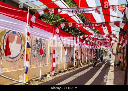 Bandung Regency, Indonésie. 12 août 2024. Un motocycliste passe devant une route aux décorations rouges et blanches accueillant le 79ème jour de l’indépendance de la République d’Indonésie, et 70 mètres de tissu rouge et blanc décorent le village de Cileunyi Kulon, Bandung Regency, Java occidental. (Photo de Dimas Rachmatsyah/Pacific Press) crédit : Pacific Press Media production Corp./Alamy Live News Banque D'Images