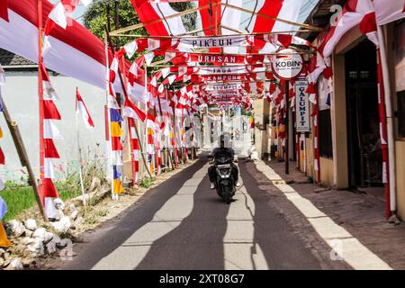 Bandung Regency, Indonésie. 12 août 2024. Un motocycliste passe devant une route aux décorations rouges et blanches accueillant le 79ème jour de l’indépendance de la République d’Indonésie, et 70 mètres de tissu rouge et blanc décorent le village de Cileunyi Kulon, Bandung Regency, Java occidental. (Photo de Dimas Rachmatsyah/Pacific Press) crédit : Pacific Press Media production Corp./Alamy Live News Banque D'Images