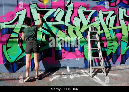 Artiste graffiti femme peignant une peinture murale sur le côté d'un bâtiment lors d'un festival mural, Vancouver, BC, Canada Banque D'Images