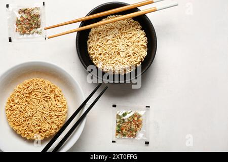 Crues les nouilles instantanées dans des bols avec des baguettes et assaisonnements sur fond de grunge blanc Banque D'Images
