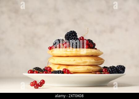 Assiette de crêpes sucrées avec des mûres fraîches et des groseilles rouges sur fond blanc Banque D'Images