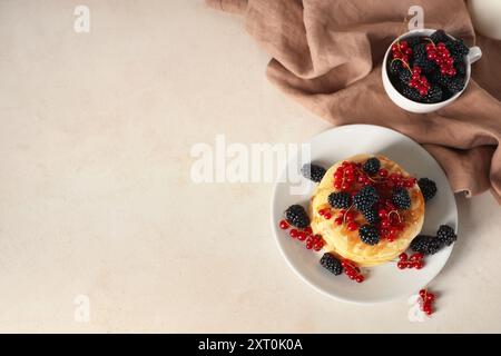 Assiette de crêpes sucrées avec des mûres fraîches et des groseilles rouges sur fond blanc Banque D'Images