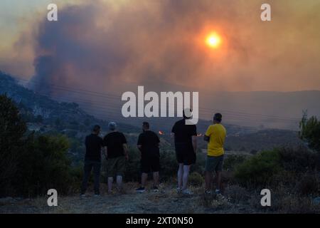 Athènes, Grèce. 12 août 2024. Les résidents observent le front de feu à l'approche de la banlieue de Penteli dans la capitale grecque. Un feu de forêt qui a éclaté à Varnavas le 11 août a continué de faire rage dans l'est de l'Attique le 12 août, attisant et s'étendant sur un front s'étendant sur plus de 20 kilomètres. Plusieurs pays ont répondu positivement à la demande d'assistance du mécanisme de protection civile de l'UE (EUCPM) formulée par les autorités grecques pour lutter contre les incendies de forêt qui font rage. Crédit : Dimitris Aspiotis/Alamy Live News Banque D'Images