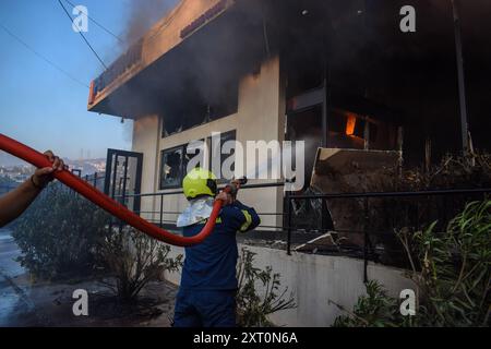 Athènes, Grèce, 12 août 2024. Un pompier éteint le feu dans un magasin de la banlieue de Vrilissia, dans la capitale grecque. Un feu de forêt qui a éclaté à Varnavas le 11 août a continué de faire rage dans l'est de l'Attique le 12 août, attisant et s'étendant sur un front s'étendant sur plus de 20 kilomètres. Plusieurs pays ont répondu positivement à la demande d'assistance du mécanisme de protection civile de l'UE (EUCPM) formulée par les autorités grecques pour lutter contre les incendies de forêt qui font rage. Crédit : Dimitris Aspiotis/Alamy Live News Banque D'Images