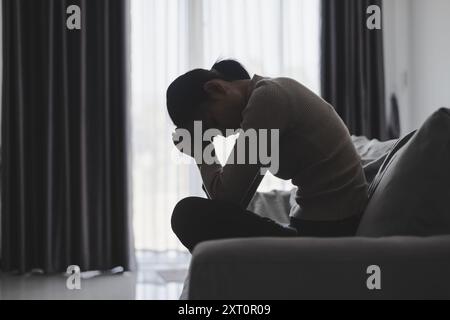 Souffrez de dépression , problème de santé mentale. jeune femme asiatique assise sur le canapé se sentant déprimée. Les femmes sont stressées et déprimées. Banque D'Images