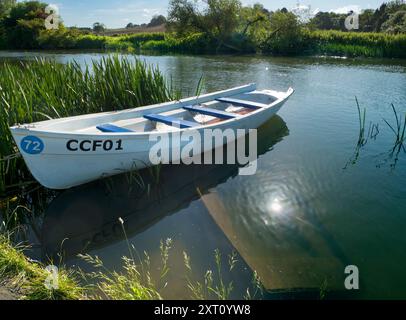 Fondé en 1921 et situé sur une belle partie de la Tamise dans l'Oxfordshire, Radley Boathouse sert Radley College et les amateurs d'aviron locaux depuis plus d'un siècle. Ici, nous voyons un bateau à rames amarré par sa jetée, tôt par un beau matin d'été. Il flotte au-dessus d'un compagnon submergé et coulé. Banque D'Images