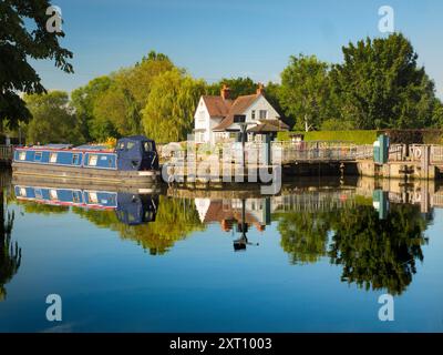 La zone autour de Sandford Lock Over the Thames est un endroit très apprécié des joggeurs, promeneurs, amateurs de chiens et beaucoup de gens fréquentant les grandes promenades dans cette région. Un nouveau boulanger artisanal proposant du pain au levain à la pointe est désormais une attraction locale... Ici, nous voyons des péniches amarrées par l'écluse, avec la maison d'écluse en arrière-plan, tôt un beau matin d'été. Je suis en route pour ramasser le pain. C'est le petit déjeuner trié, alors ! Banque D'Images