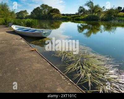 Fondé en 1921 et situé sur une belle partie de la Tamise dans l'Oxfordshire, Radley Boathouse sert Radley College et les amateurs d'aviron locaux depuis plus d'un siècle. Ici, nous voyons deux bateaux à rames amarrés par sa jetée, tôt par un beau matin d'été. Banque D'Images