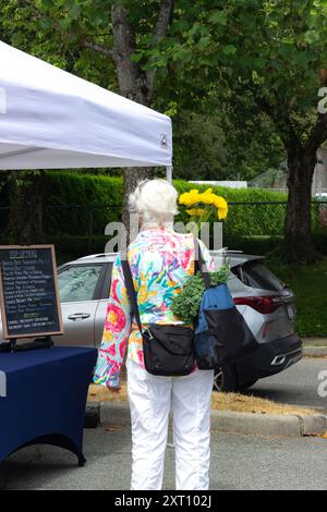 Une personne âgée achetant des fleurs au marché fermier Banque D'Images