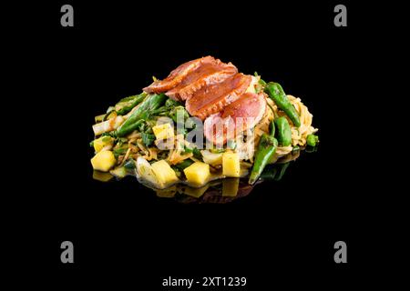 Un plat coloré sauté avec des ​​meat tranchées et une variété de légumes, y compris des asperges, des poivrons et de l'ananas, servi sur des nouilles frites Banque D'Images