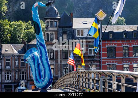 Dinant, Namur, Wallonie, Belgique. 5 juin 2024. Sculpture de saxophone bleu et drapeaux de différents pays européens sur le pont au-dessus de la rivière Meuse, touristique Banque D'Images