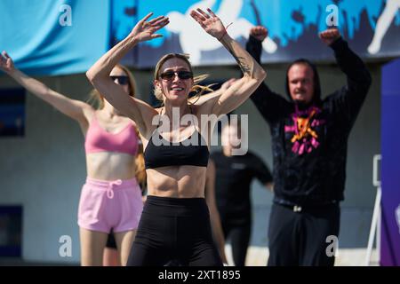 Femme ukrainienne joyeuse faisant l'exercice de saut de jack à l'entraînement de groupe en plein air en été. Kiev - 10 août 2024 Banque D'Images