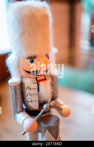 Casse-noisette blanc décoratif avec fourrure blanche Bearskin Hat un costume argenté et un tambour debout sur une table avec un sapin en céramique Banque D'Images