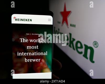 Personne tenant le smartphone avec la page Web de la brasserie néerlandaise Heineken N.V. devant le logo de l'entreprise. Concentrez-vous sur le centre de l'écran du téléphone. Banque D'Images