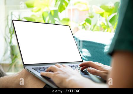 Personne travaillant sur un ordinateur portable avec un écran vide, dans un environnement lumineux et vert plein de plantes. Image parfaite pour présenter les interfaces utilisateur, à distance Banque D'Images