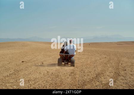 Deux personnes sur un VTT chevauchant un vaste paysage désertique sous un ciel dégagé. Bola02563 Copyright : xConnectxImagesx Banque D'Images