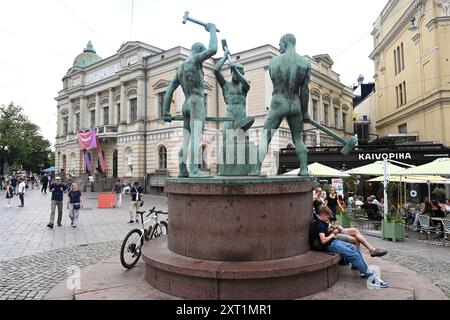 Helsinki, Finlande - 25 juillet 2024 : un peuple près de la statue des trois forgerons et de la vieille maison des étudiants à Helsinki. Banque D'Images