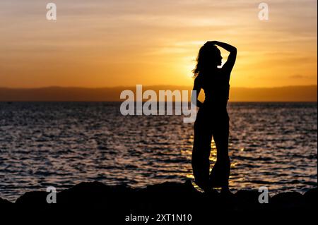 Silhouette d'une femme debout près de la mer au coucher du soleil, posant la main dans ses cheveux. Philippines rist00009 Copyright : xConnectxImagesx Banque D'Images