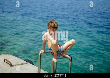 Garçon en maillot de bain se préparant à plonger dans l'océan depuis une corniche rocheuse. Hydra Grèce bola02674 Copyright : xConnectxImagesx DATE D'ENREGISTREMENT NON INDIQUÉE Banque D'Images