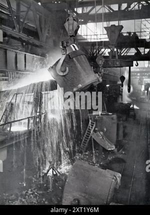 Une photographie montre des grues transportant du métal liquide pour le couler dans une fonderie allemande pendant la seconde Guerre mondiale. Cette image met en évidence les efforts industriels intenses de l'Allemagne nazie pour soutenir sa machinerie de guerre. Des fonderies comme celle-ci ont joué un rôle crucial dans la production du métal nécessaire aux armes, aux véhicules et aux infrastructures. Banque D'Images