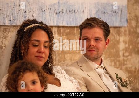 Une mariée et le marié s'assoient côte à côte avec un jeune enfant au premier plan, tous habillés dans une tenue formelle pour une cérémonie de mariage. Panc06022 Copyright : XCO Banque D'Images