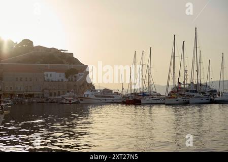 Le coucher du soleil brille derrière une forteresse perchée surplombant une marina sereine bordée de voiliers amarrés. Bola02783 Copyright : xConnectxImagesx Banque D'Images