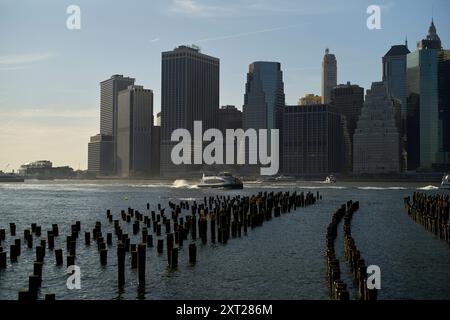 Vue sur le coucher du soleil de la ville de New York avec des restes de jetée silhouette au premier plan et des bateaux sur l'eau. Bola02877 Copyright : xConnectxImagesx Banque D'Images