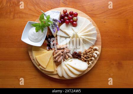 Tableau des différents fromages présentés avec des raisins, des noix, quelques feuilles de menthe et des fleurs de lavande Banque D'Images