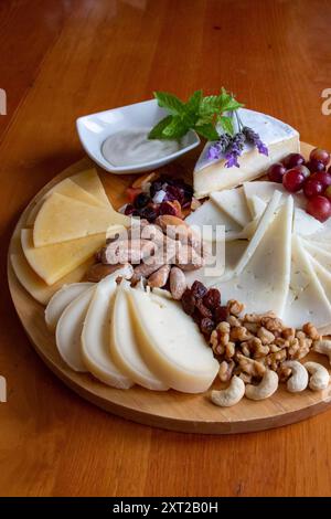 Tableau des différents fromages présentés avec des raisins, des noix, quelques feuilles de menthe et des fleurs de lavande Banque D'Images