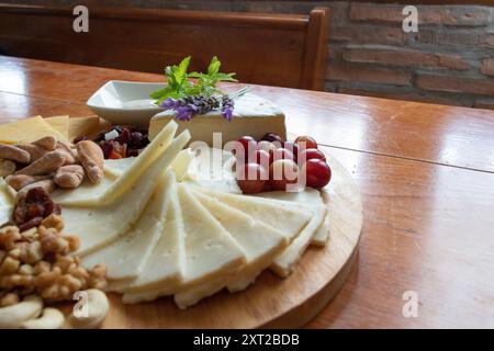 Tableau des différents fromages présentés avec des raisins, des noix, quelques feuilles de menthe et des fleurs de lavande Banque D'Images