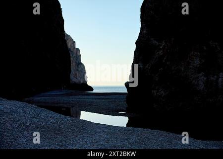 Une crique tranquille aux eaux calmes nichée entre d'imposantes falaises sous un ciel crépusculaire. Bola02935 Copyright : xConnectxImagesx DATE D'ENREGISTREMENT NON INDIQUÉE Banque D'Images